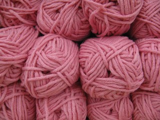 Set of pink wool yarn balls. Hanks are set out in a pile.