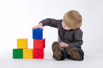 little boy plays with colorful cubes