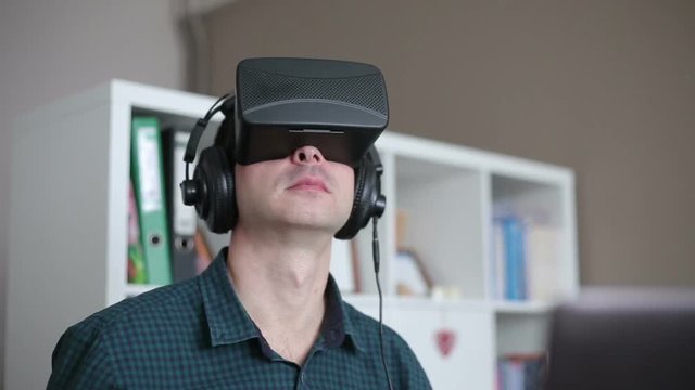 Young Man in the Special Headset at the Laptop