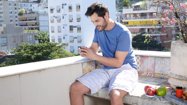 Young man sitting out on patio and texting