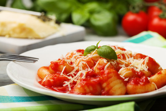 Serving gnocchi in tomato sauce with cheese.