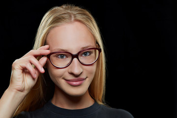 Junge Frau lächelt mit Hand an Brille