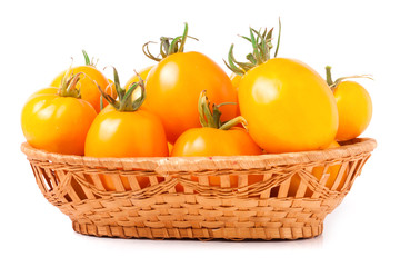 yellow tomatoes in a wicker basket isolated on white background