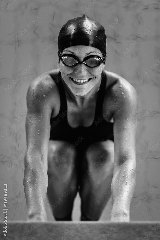 Wall mural Female swimmer at pool edge. looking up, smiling