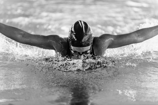 Butterfly stroke swimmer, front view, black and white