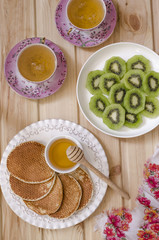 Pancakes with honey and a cup of tea of coffee for breakfast  