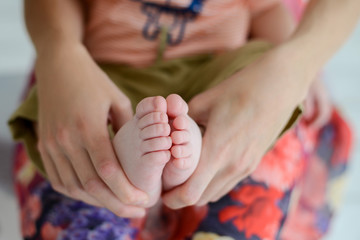 Mother holds the feet of the newborn child