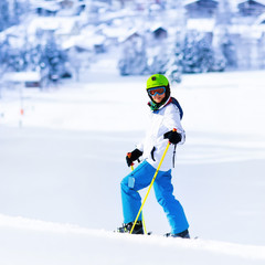 Fototapeta na wymiar Child skiing in mountains. Active teen age kid with safety helmet, goggles and poles. Ski race for young children. Winter sport for family. Kids ski lesson in alpine school. Skier racing in snow