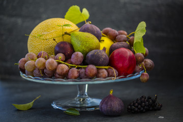 Beautiful still life with grapes and figs and other fruits on stone background.
