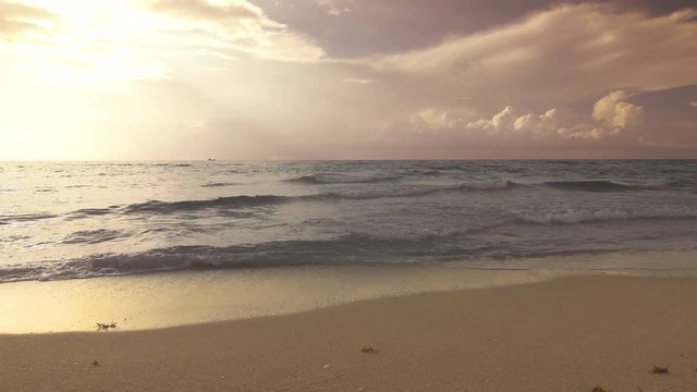 Sunrise beach with soft sand and calm ocean waves with boat on the horizon, shot in South Beach, Miami, Florida