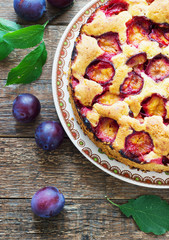 rustic plum cake on dark wooden background
