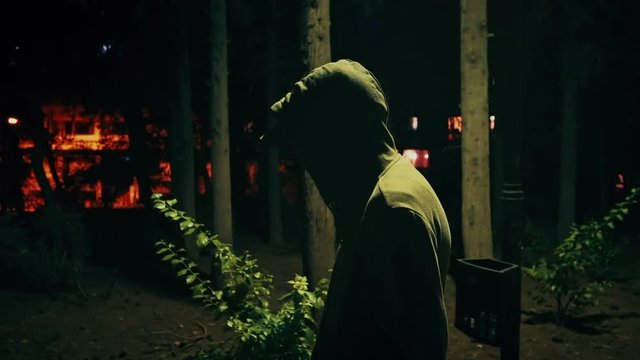 Suspicious hooded figure walks in a dark park at night,100p