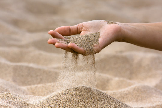 sand running through hand of woman