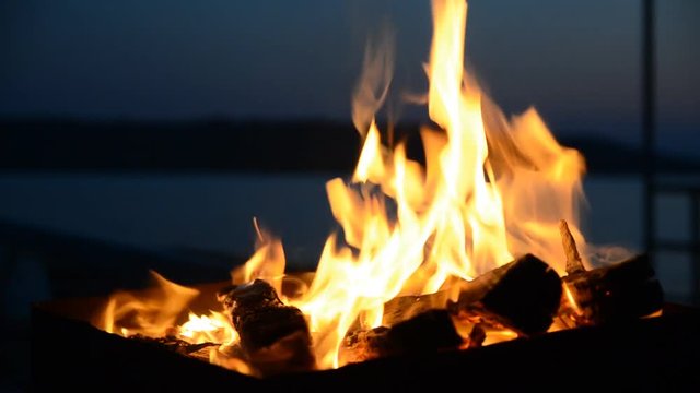 The firewood burning in a brazier closeup in the night.