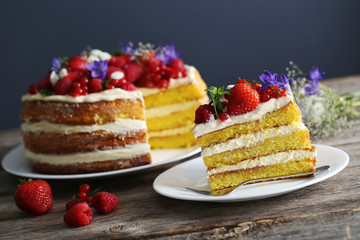Delicious biscuit cake with berries on grey wooden table