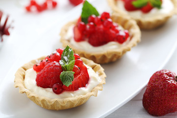 Dessert tartlets with berries on white wooden background