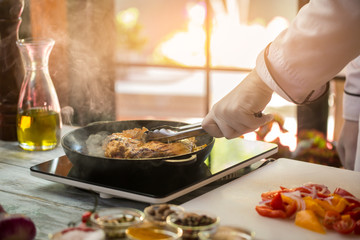 Tongs touch fried meat. Cut onion and tomatoes. How to prepare juicy pork. Dish for true gourmets.