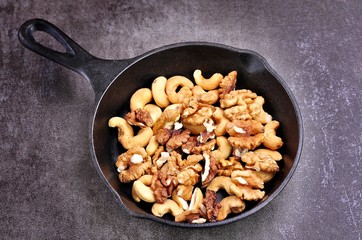 Roasted walnuts and cashews on a cast iron pan. 