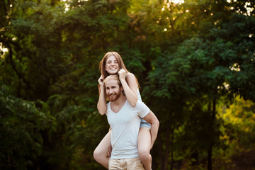 Young beautiful couple resting, walking in park, smiling, rejoicing. Outdoor background.