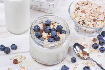 Yogurt with blueberry and cereal of glass in a jar on a wooden t