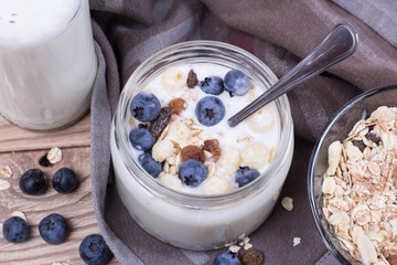 Yogurt with blueberry and cereal of glass in a jar on a wooden t