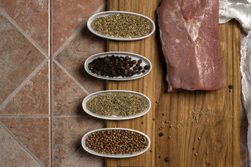 Fresh meat selection on wooden cutting board with spices in a white bowl