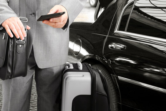 Traveling Businessman with His Luggage Using Phone 