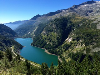 Blick auf einen türkisblauen Stausee im Gebirge