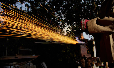 Worker cutting metal with grinder. Sparks while grinding iron