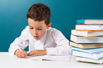 Pensive cute boy with homework sitting at a table