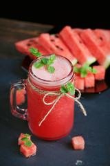 Delicious fresh watermelon cocktail, pieces of chocolate and cinnamon on the dark background.