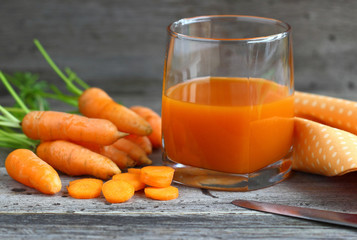 glass of carrot juice and fresh carrots on wooden table