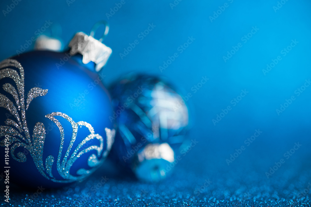 Wall mural Blue xmas ornaments on dark blue glitter background with space for text. Merry christmas card. Winter holiday theme. Happy New Year.