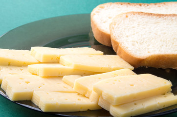 Cut slices of cheese on a plate closeup