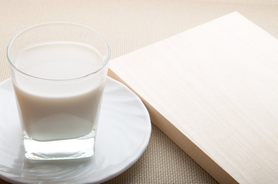 Glass of milk on a white saucer on textile background