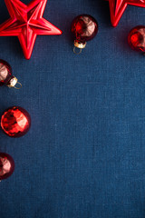 Red christmas decorations (stars and balls) on dark blue canvas background. Merry christmas card. Winter holidays. Xmas theme. Happy New Year.