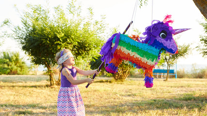 Young girl at an outdoor party hitting a pinata © sarymsakov.com