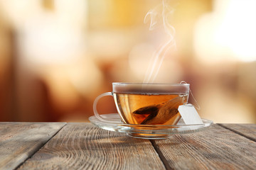 Glass cup of tea on wooden table and blurred color background