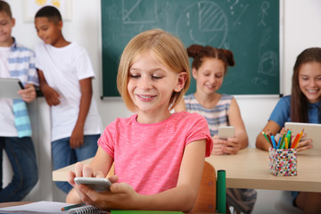 Schoolgirl with mobile phone sitting in classroom