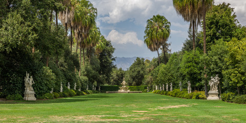 Large garden lined with trees with sky and mountains view