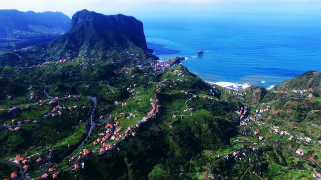 Aerial view of ocean sea rocky coast. Portugal Madeira island village city landscape 4k travel video background. Flight over forest hills, houses, blue water