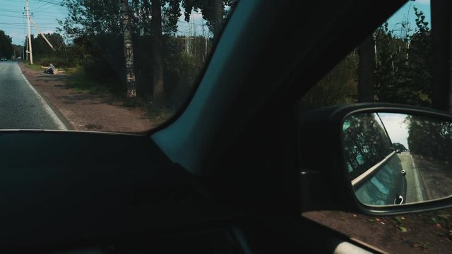Car passes young boy hitchhiking at road. Traveler. Thumb up. Summer day. Camera inside car