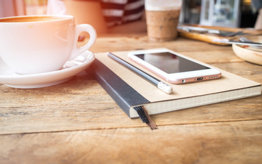 Mobile phone and diary notebook with coffee cup on wood backgrou