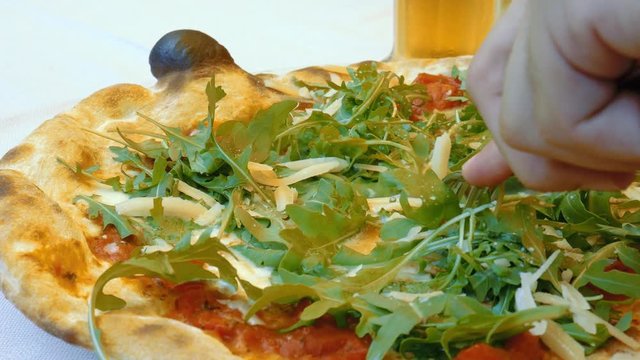 Cutting Italian Pizza topped with parmesan cheese and delicious arugula
