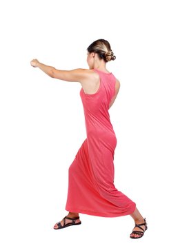 skinny woman funny fights waving his arms and legs. slender woman in a long red dress strikes a hand.