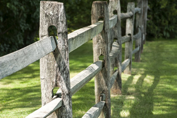 Old weathered wooden fence in park in summer day