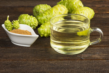 Noni fruit and noni juice with noni powder on black table.Fruit for health and herb for health