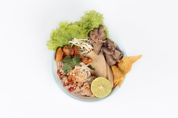 Noodle with tom yam topped with minced pork,chicken liver,wonton,shrimp ,chili. and green lemon on white background.