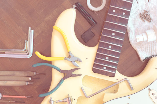 yellow electric guitar on wood in repair & luthier workshop, fixing & musical instrument repairing concept