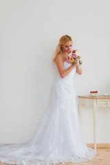 Fototapeta na wymiar Portrait of a beautiful blonde bride with bouquet in an interior light, wedding concept